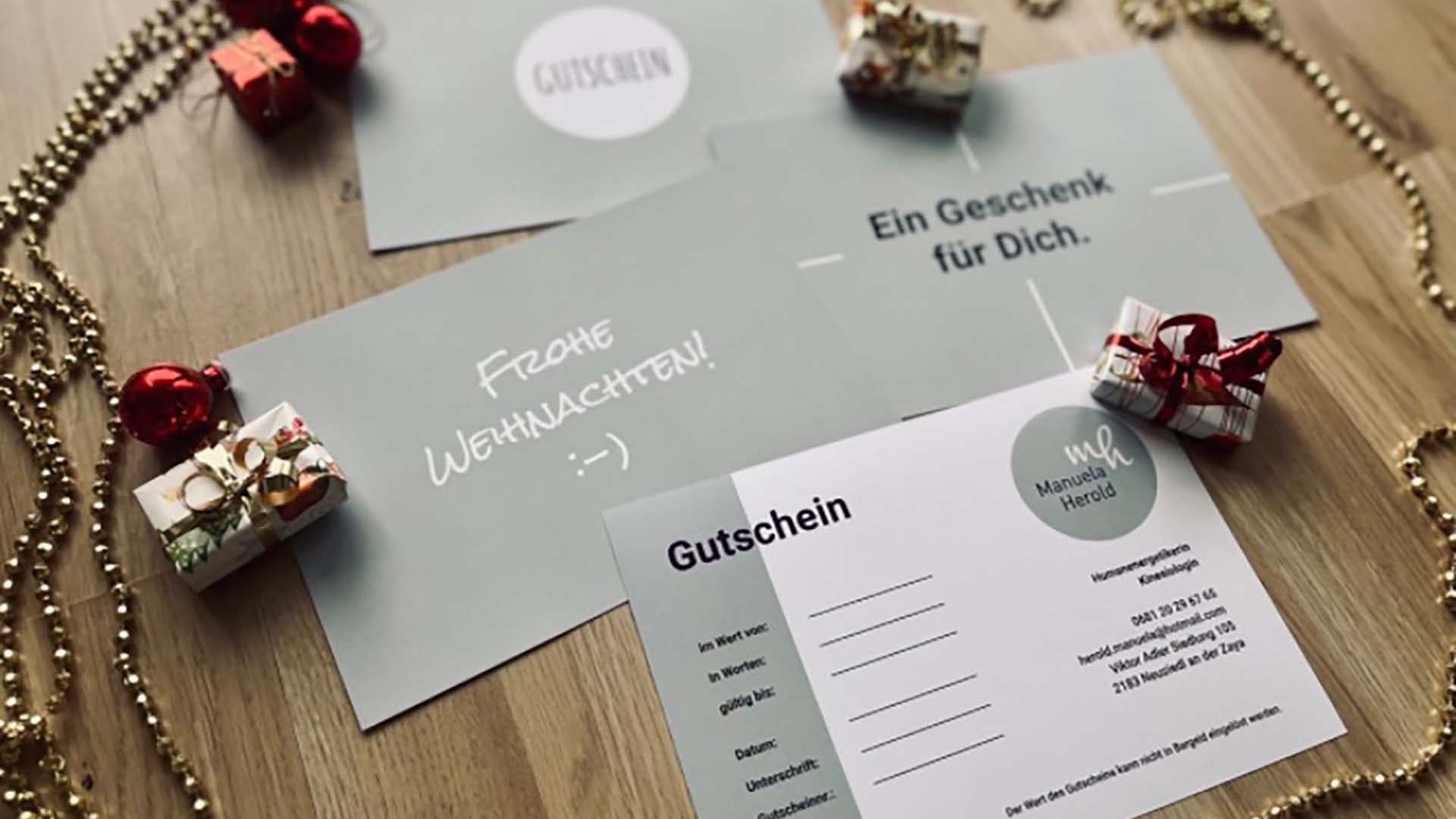Foto von Gutscheinen für Sitzungen von Manuela Herold. Diese liegen auf einem Holztisch und sind umringt von Weihnachtsdekorationen.